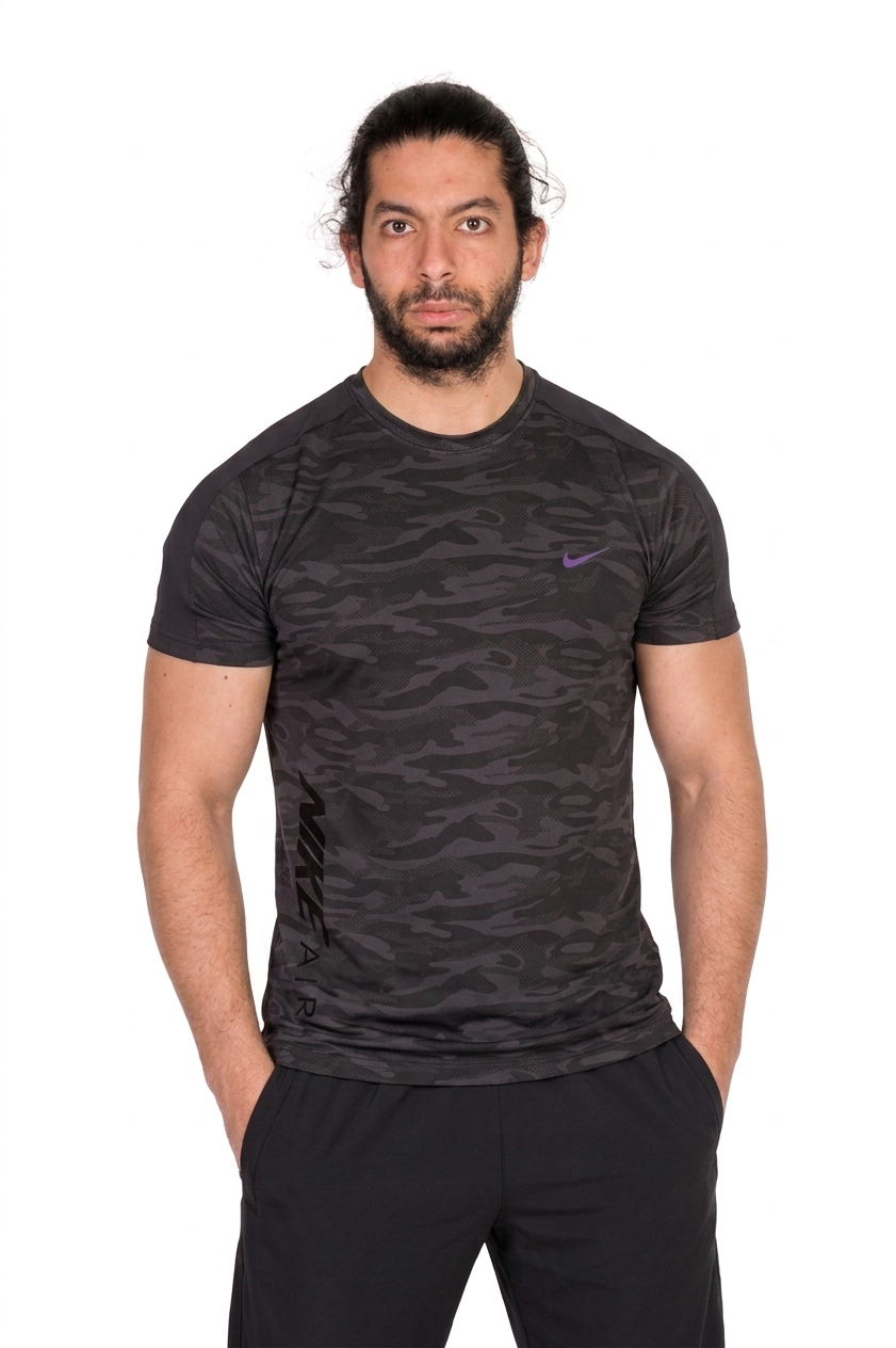Man wearing a black patterned athletic shirt with a visible brand logo on a background