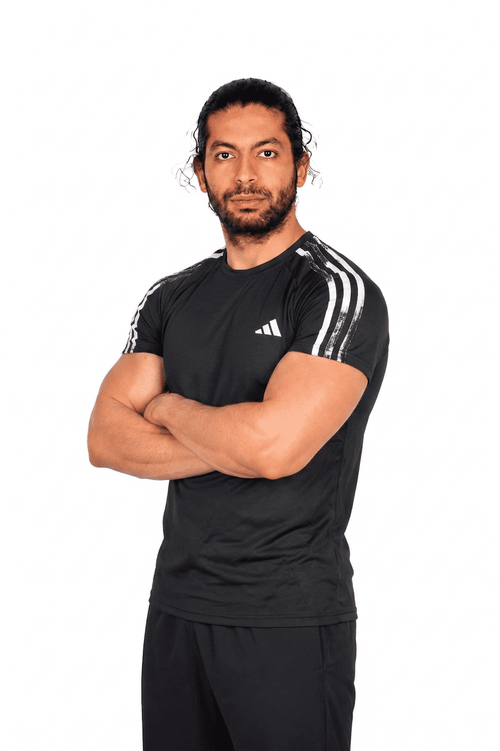 Man wearing a black Adidas sports outfit with arms crossed on a white background