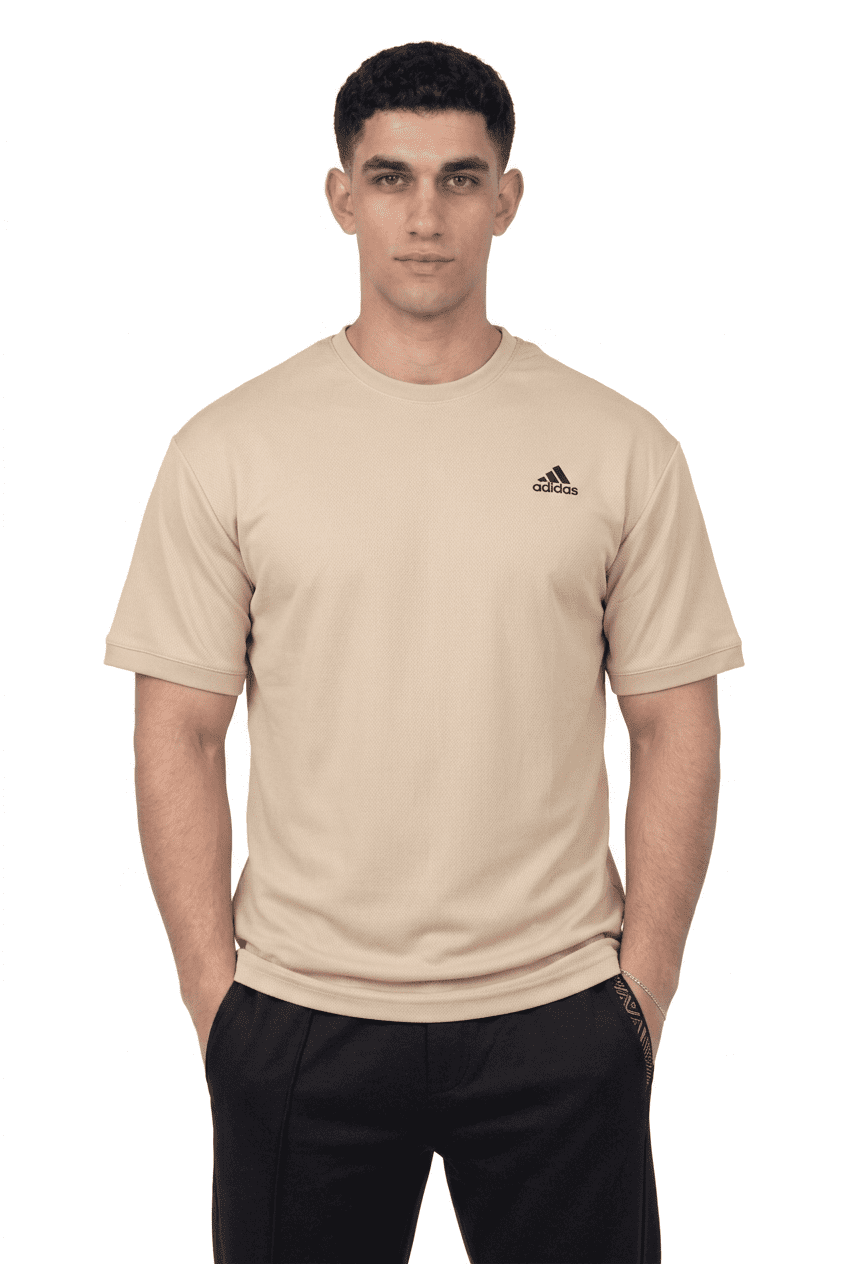Person wearing a beige Adidas t-shirt on a background